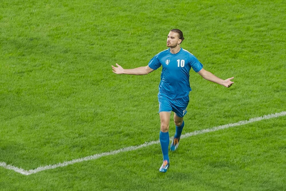 Soccer Football Championship: Blue Team Forward Running Excited After Scoring a Goal in Finals. Team Celebrates. Winners of the Tournament, Crowd of Fans Cheer. Sport TV Broadcast Concept. High Angle.