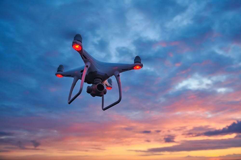 drone quadcopter with digital camera flying at sunset