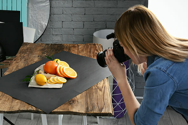 Lady taking photos of food on a wooden table in home photo studio