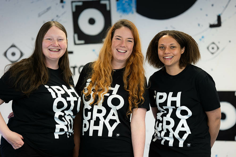 3 women stood next to each other in photography tshirts